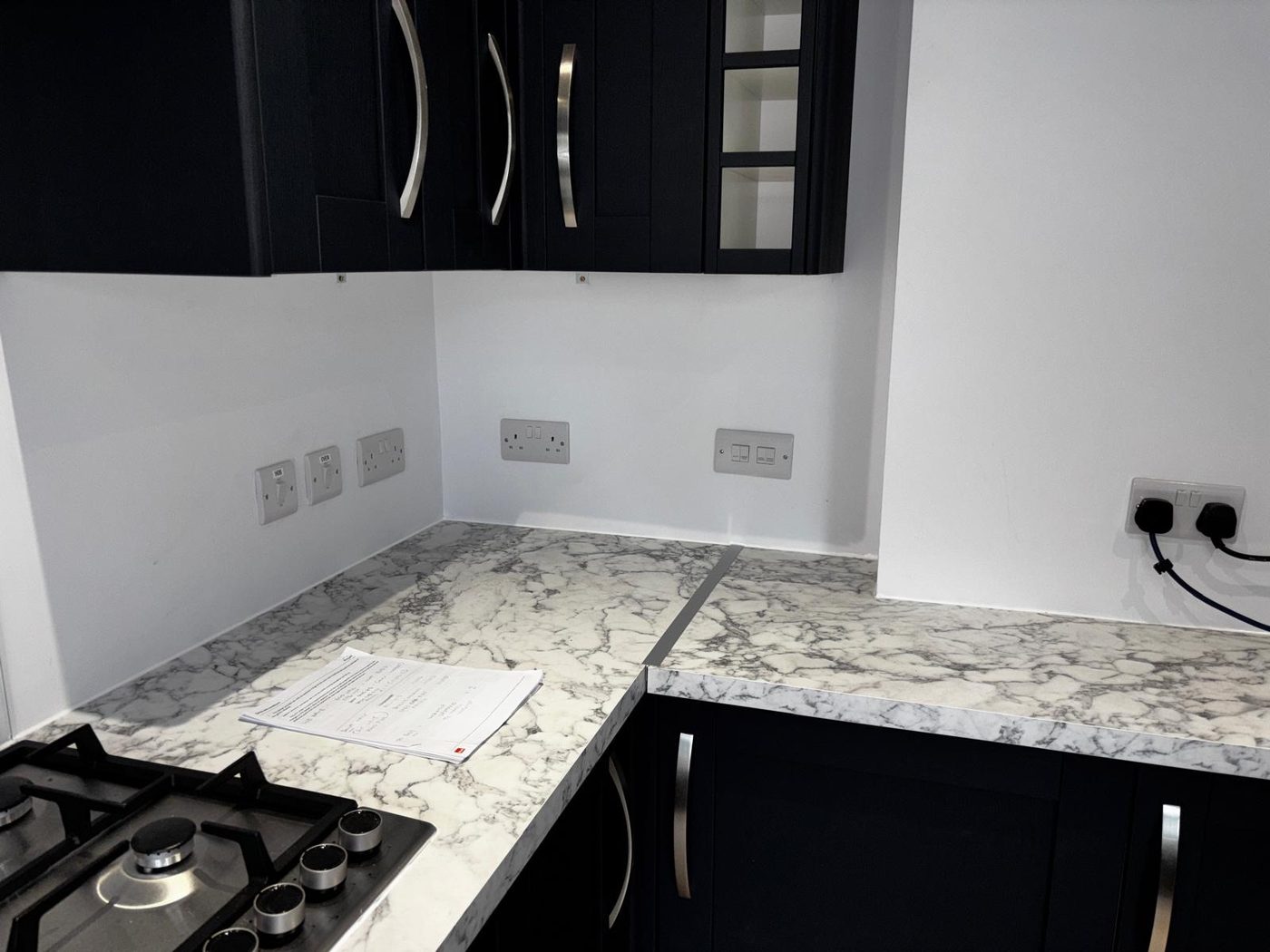A finished navy kitchen with sockets and switches fitted