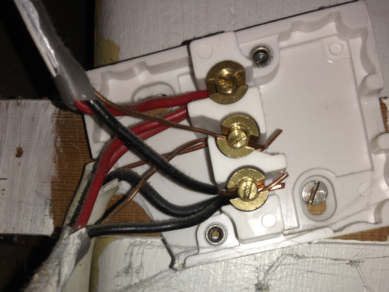 Damaged, uncovered junction box hidden behind a wardrobe